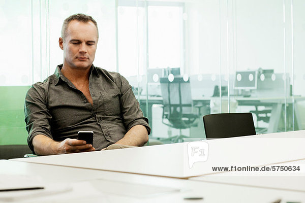 Erwachsener Mann mit Handy am Konferenztisch