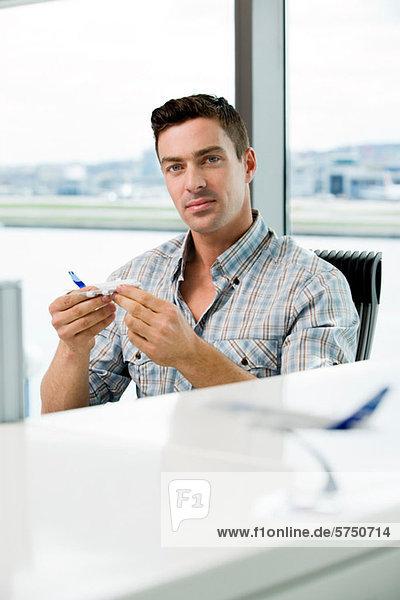 Young man looking at model aeroplane in office