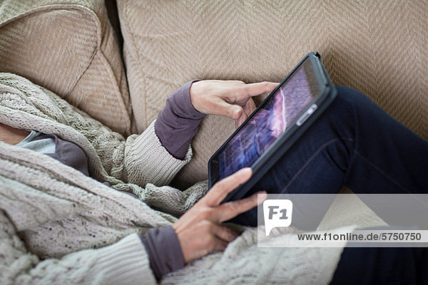 Senior woman using digital laptop on sofa  mid section