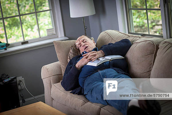 Senior man sleeping on sofa in living room