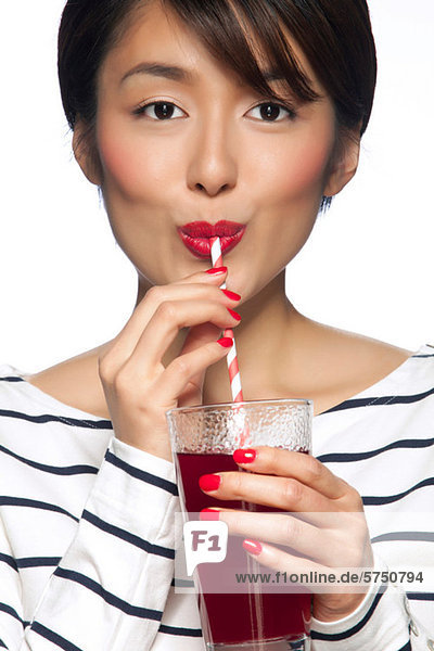 Young woman drinking from straw against white background