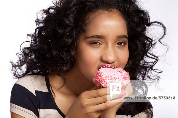 Young woman eating cupcake  studio shot