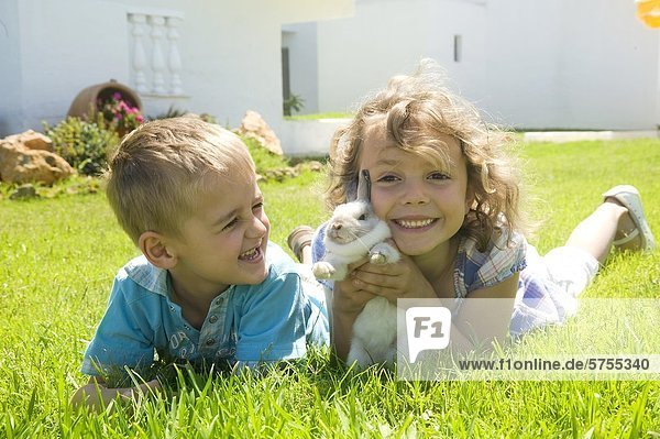 Junge und Mädchen spielen mit einem Hasen