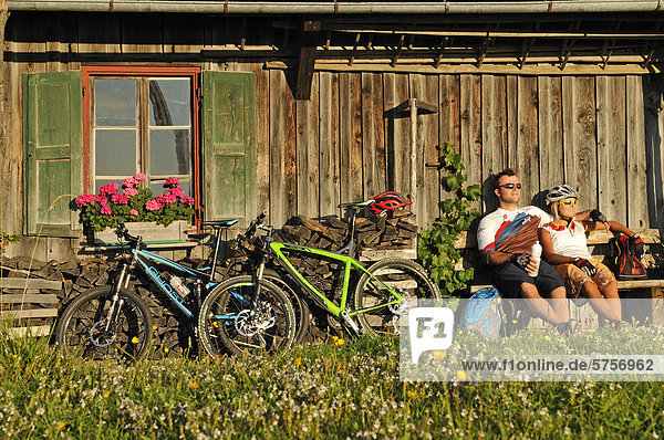 Mountain bikers resting in front of an old farmhouse on Kraftalm alp  Mt Hohe Salve  Kitzbuehel Alps  Tyrol  Austria  Europe