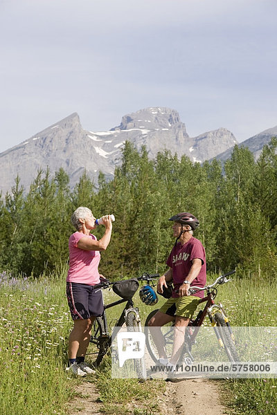 Active  fit  elderly couple mountain biking on trail in Fernie  British Columbia  Canada.