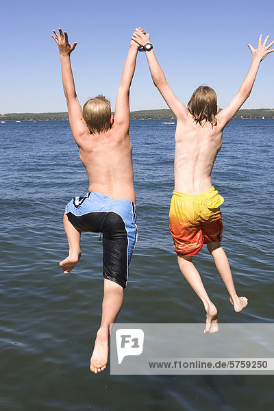 zwei jungen (9 & 12 Jahre alt) einen Sprung aus Dock in See  Sylvan Lake  Alberta  Kanada.
