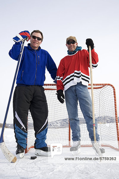35 & 45 year old playing hockey on frozen lake  Alberta  Canada.