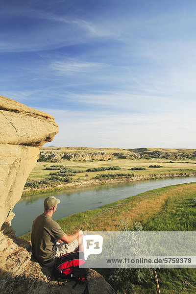 Hiker looking out over the Milk River from amid the hoodoos in Writing-on-Stone Provincial Park  Alberta  Canada.