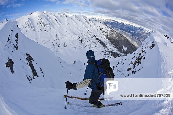 A middle aged man contemplates before dropping into a steep chute   Kicking Horse Backcountry  Golden  Britsh Columbia  Canada