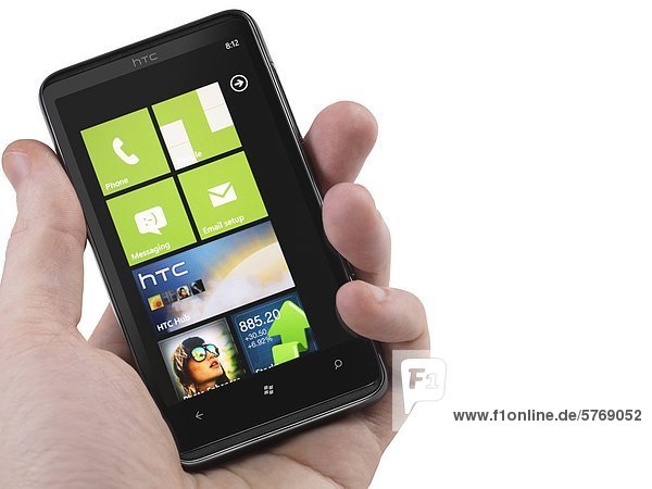Hand with a Windows 7 phone. HTC HD7 smartphone with desktop tiles on its display