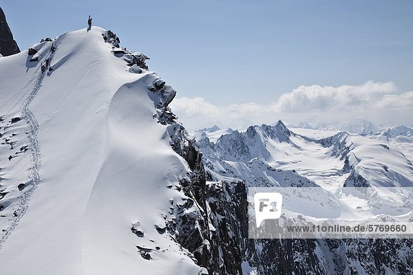 Backcountry skiers climb to top of ridge in the Selkirk Range near the Fairy Meadows backcountry hut  British Columbia  Canada.