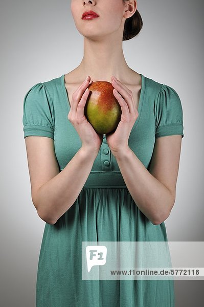 Junge Frau hält eine Mango