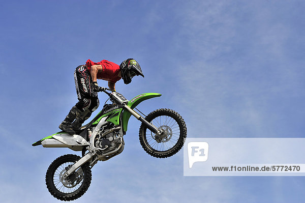 A motocross rider performing a stunt while jumping through the air.