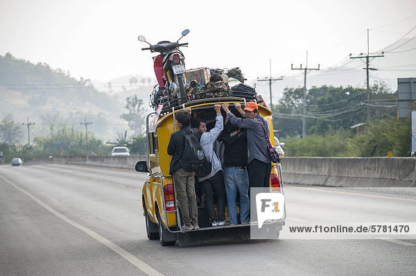 Voll beladenes Sammeltaxi oder Songthaeo oder Songthaew auf der Straße  Motorrad auf dem Dach  Nordthailand  Thailand  Asien