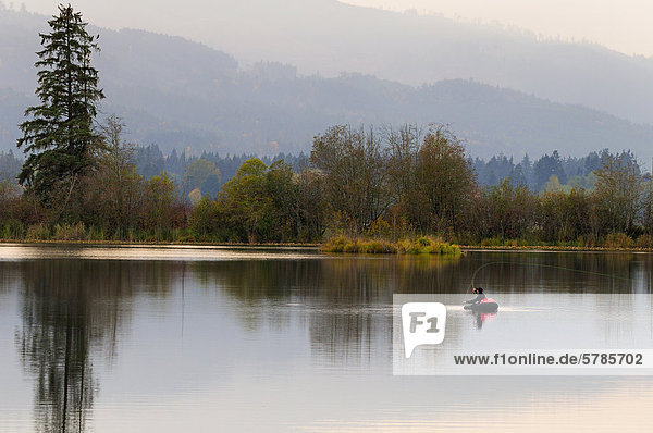 A man fly fishing in a float tube on Dougan Lake near Cobble Hill  BC.