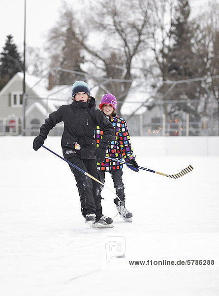 Boys playing ice hockey  on an outdoor neighborhood rink  Winnipeg  Manitoba  Canada
