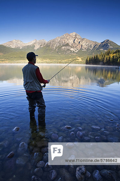 Middle age man fly fishing at Pyramid Lake  Jasper National Park  Alberta  Canada.