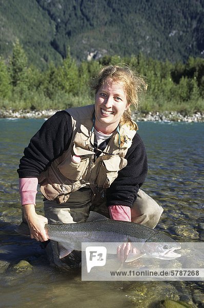 Lady angler holding steelhead  Dean river  British Columbia  Canada.
