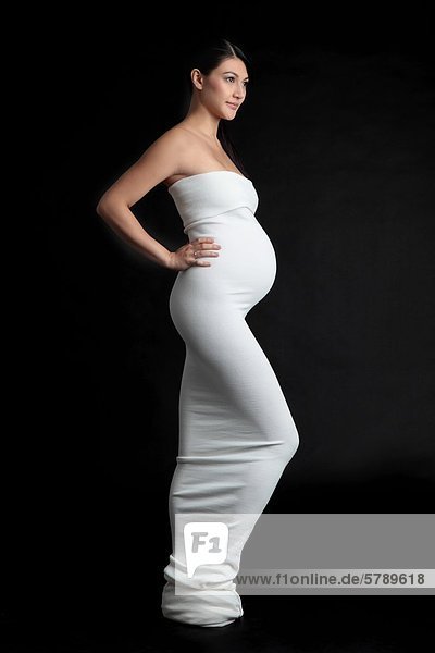 Stehende schwangere Frau in elegantem Kleid
