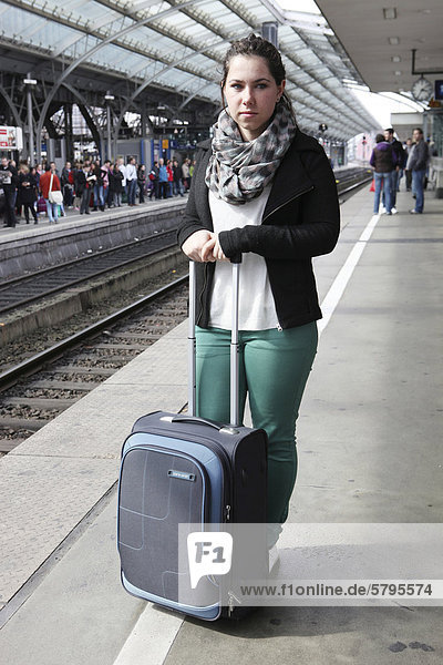 Young woman with a suitcase standing on the platform  railway station  Cologne  North Rhine-Westphalia  Germany  Europe