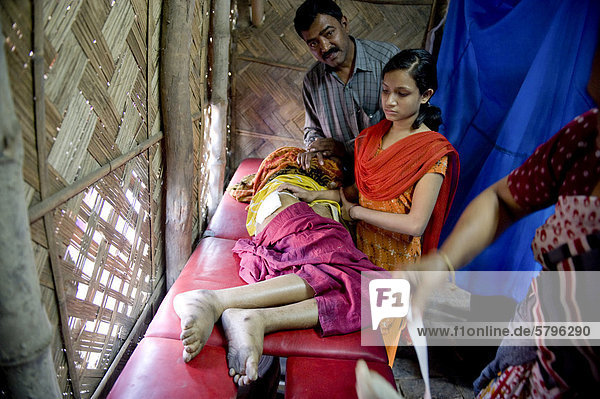 'Patient lying on a trolley or gurney  clinic set up in a bamboo hut by the aid organisation ''Aerzte fuer die Dritte Welt''  German for ''Doctors for the Third World''  German Doctors  Shibpur district  Haora or Howrah  Calcutta  Kolkata  West Bengal  India  Asia'