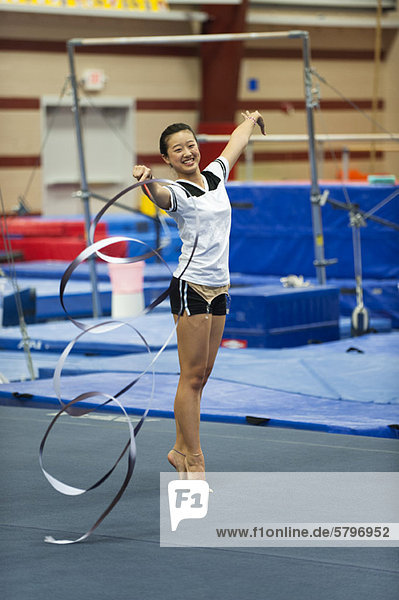 Teenage girl gymnast practicing rhythmic gymnastics  twirling ribbon