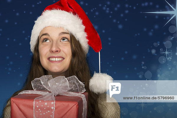 Junge Frau mit Weihnachtsmütze  mit Weihnachtsgeschenk  Portrait