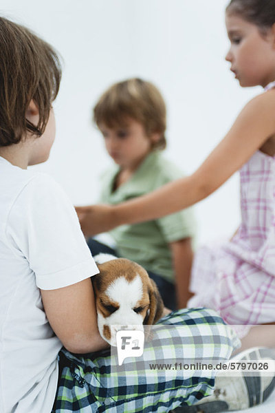 Children hanging out  boy in foreground holding beagle puppy