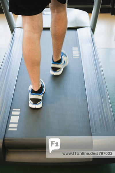 Man running on treadmill  low section  rear view