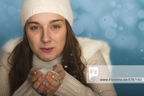Junge Frau in Winterkleidung  hält eine Handvoll Konfetti  Porträt