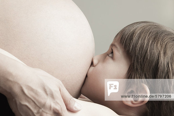 Junge  der den Bauch einer schwangeren Mutter küsst  abgeschnitten