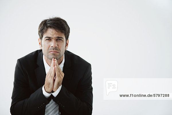 Businessman with hands clasped under chin  disappointed expression on face