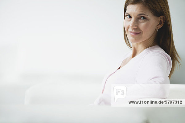 Mature woman sitting on couch  smiling over shoulder