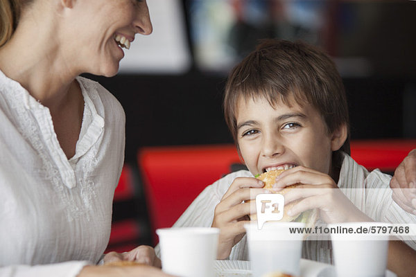 Junge isst Hamburger im Fastfood-Restaurant