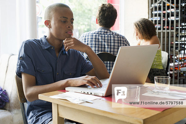 Junger Mann mit Laptop im Café
