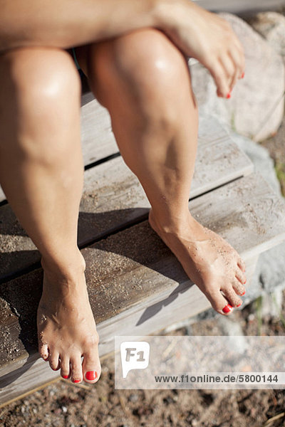 Low section of woman's legs with red nail polish