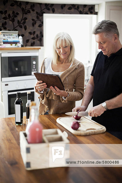 Paar in der Küche mit digitalem Tablett für Rezept und Kochmahlzeit