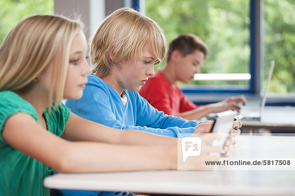 Schüler benutzen Laptop und Tablet PC im Klassenzimmer