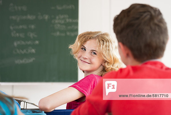 Lächelnde Schülerin im Klassenzimmer dreht sich um