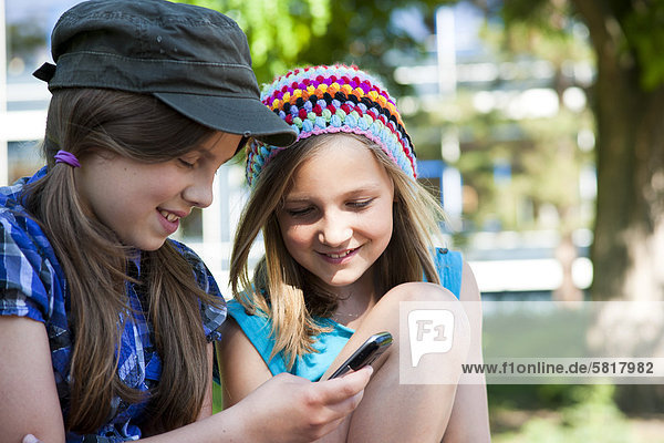 Zwei lächelnde Mädchen mit Handy