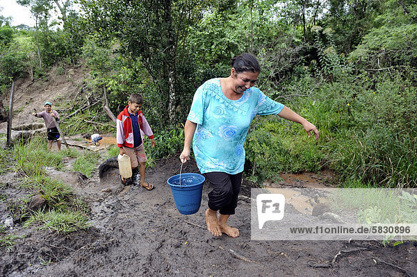 Mother and son fetching water from a stream  Comunidad Martillo  Caaguazu  Paraguay  South America