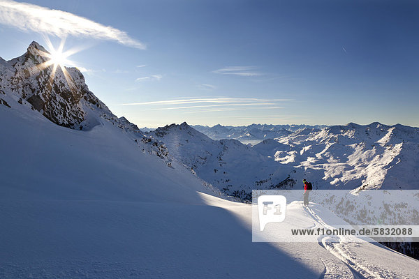Skier downhill skiing on Torspitze mountain  sun hidden behind a mountain peak  Tux Alps  northern Tyrol  Tyrol  Austria  Europe