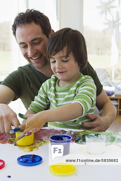 Father and son finger painting together