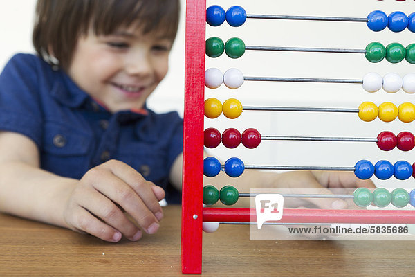 Smiling boy playing with abacus