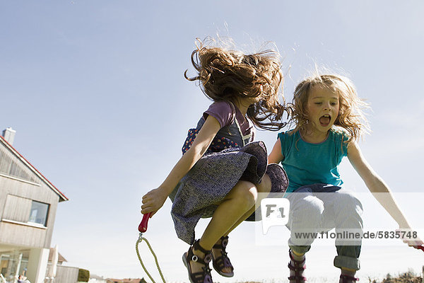 Mädchen springen zusammen im Freien.
