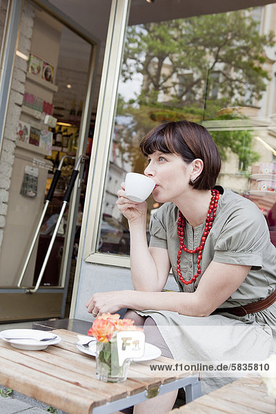 Woman having coffee at sidewalk cafe