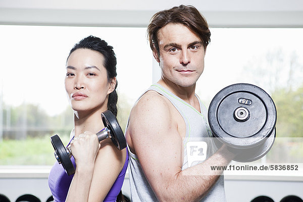Couple lifting weights in gym