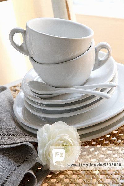 Weisse Kaffeetassen mit Untertassen und Kuchentellern