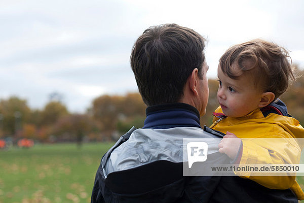 Father holding young son in park
