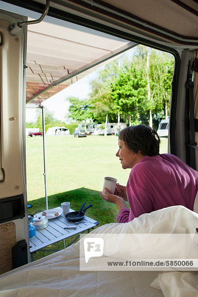 Mature woman drinking hot drink in camper van